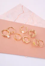 "Eight gold-toned fashion rings with artificial pearls, featuring coils, flowers, open-ended designs, and stacking bands. Perfect for versatile, trendy looks."