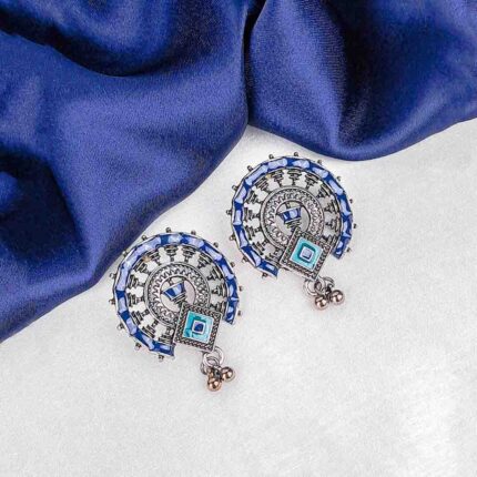 Oxidized silver half-moon stud earring with blue, brown, and green enamel detailing and a small hanging ghunghroo.