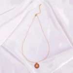 "Gold sun pendant necklace with pink center on stainless steel chain. "