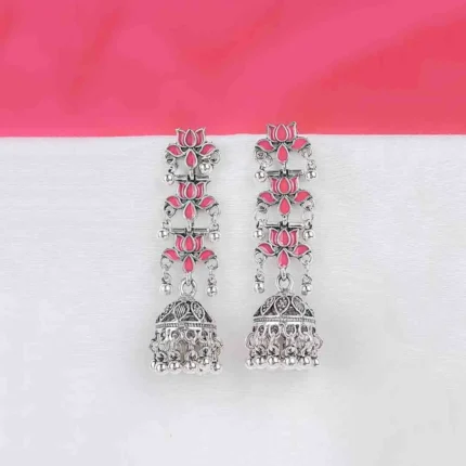Long tiered Jhumka earring featuring an oxidized silver finish. It has three linked floral sections with dark pink enamel accents, leading down to a decorative bell-shaped drop with dangling beads.