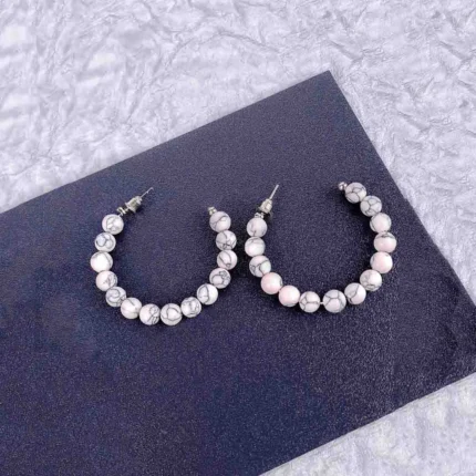 Hoop earrings with white marble beads and gray veining, polished finish, and latch-back closure.