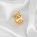 Wide-band ring with openwork lace pattern and radiant faceted crystals for statement sparkle.