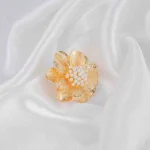 Gold-tone flower ring with textured petals and pearl cluster center, adjustable fit.