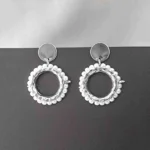 Round silver hoop earrings framed with pearls, featuring reflective studs and push-back closures.