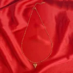 A delicate gold-toned necklace with a beaded satellite chain and a small, puffed heart pendant.
