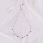 A gold-toned bracelet with a thin chain and small, dangling rectangular white gems.