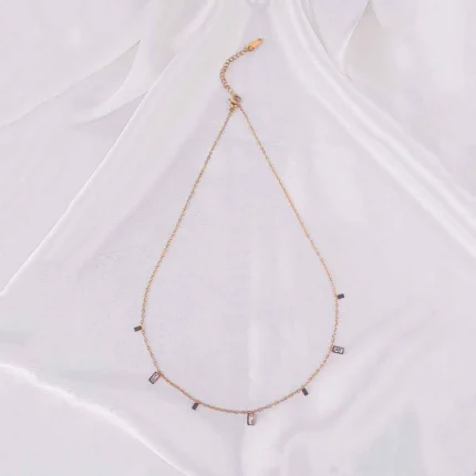 A gold-toned bracelet with a thin chain and small, dangling rectangular white gems.