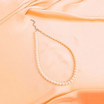 Vintage ivory pearl beaded necklace with lobster clasp, arranged in a gentle curve