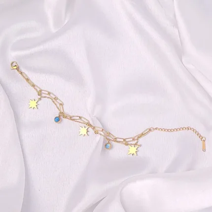  Layered gold bracelet with star charms, turquoise bead, paperclip chain, and lobster clasp.