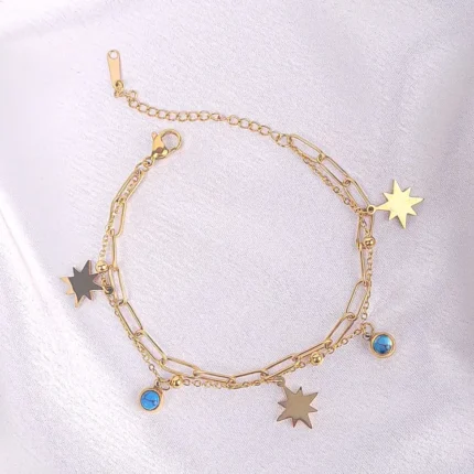  Layered gold bracelet with star charms, turquoise bead, paperclip chain, and lobster clasp.