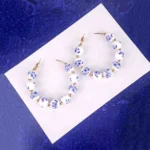 White bead hoop earrings with blue floral beads gold accents and push-back closure.