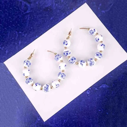White bead hoop earrings with blue floral beads gold accents and push-back closure.