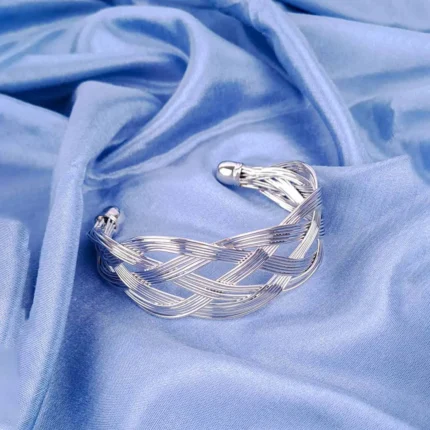 a wide gold-colored cuff bracelet featuring an intricate, woven or braided design made from multiple thin metal strands