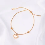 Gold adjustable chain bracelet with open heart charm, bead accents, and slider closure.