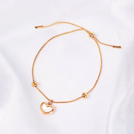 Gold adjustable chain bracelet with open heart charm, bead accents, and slider closure.